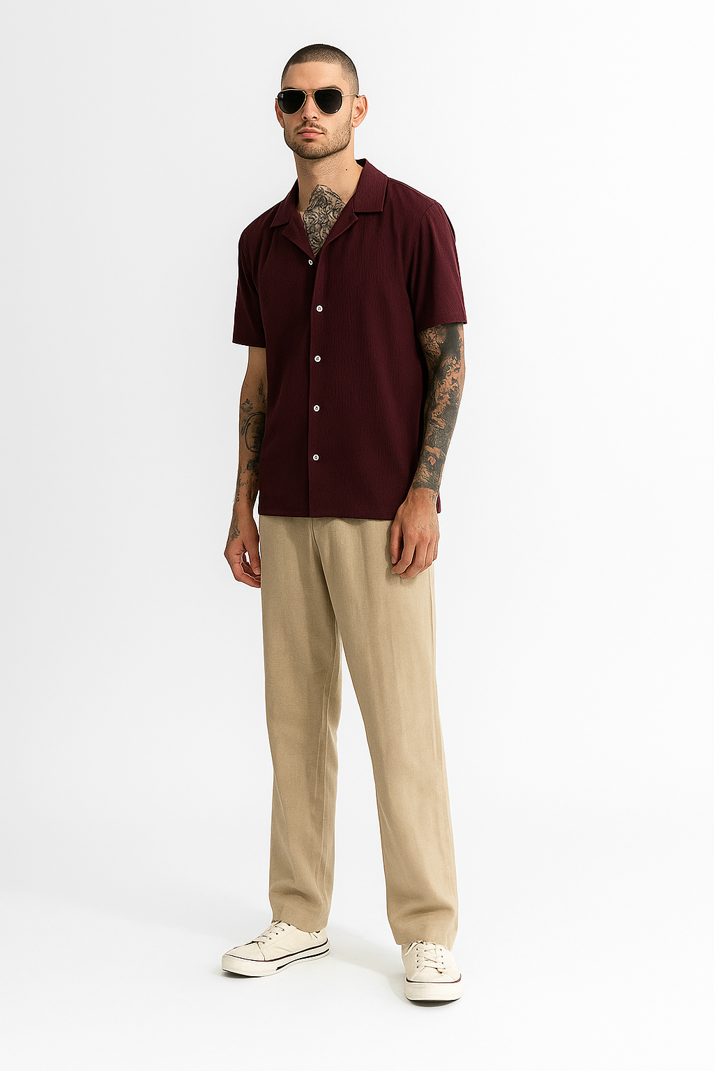 Man wearing a burgundy shirt, beige pants, and white sneakers on a white background