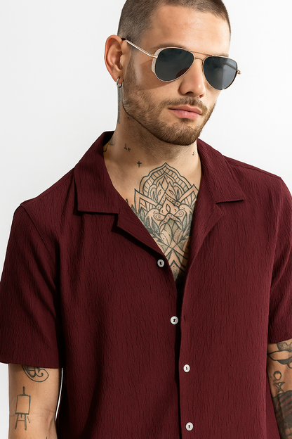 Man wearing a burgundy shirt and sunglasses on a white background