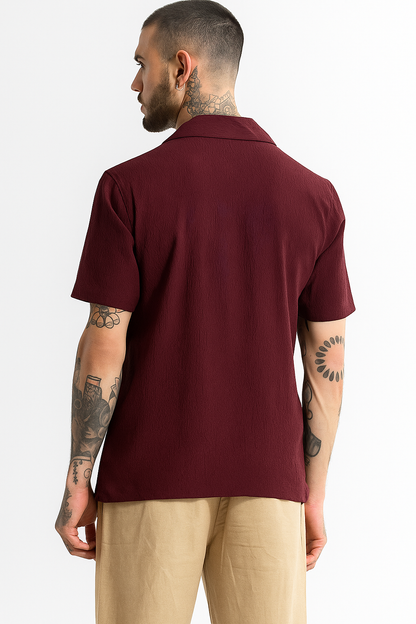 Man wearing a maroon polo shirt and beige pants on a white background