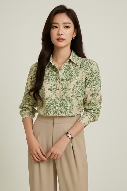 Woman wearing a green patterned shirt and beige pants on a plain background